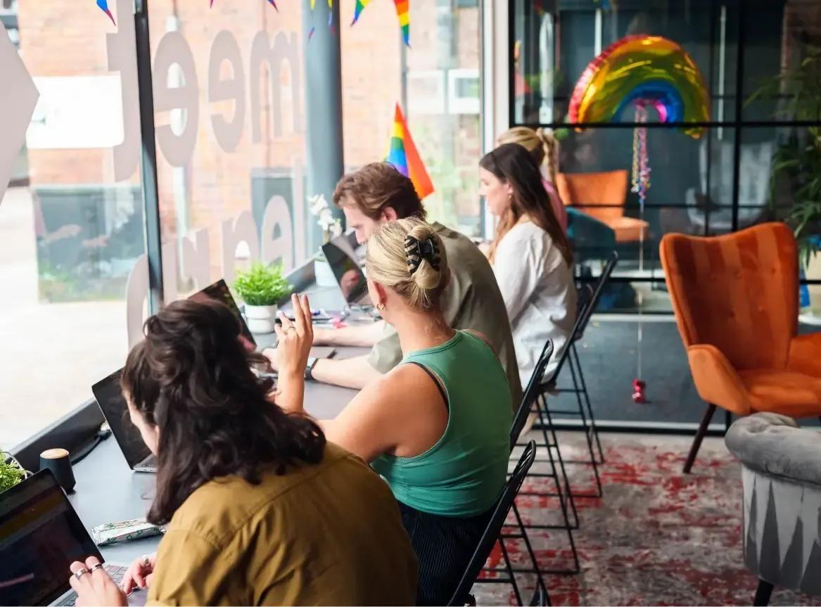Four colleagues sat working at a window
